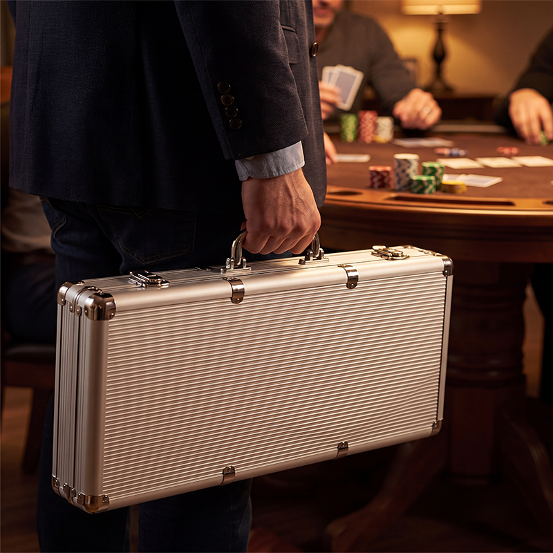 Person holding a Fat Cat Replacement Aluminum 500Ct Poker Chip Case with a poker table in the background