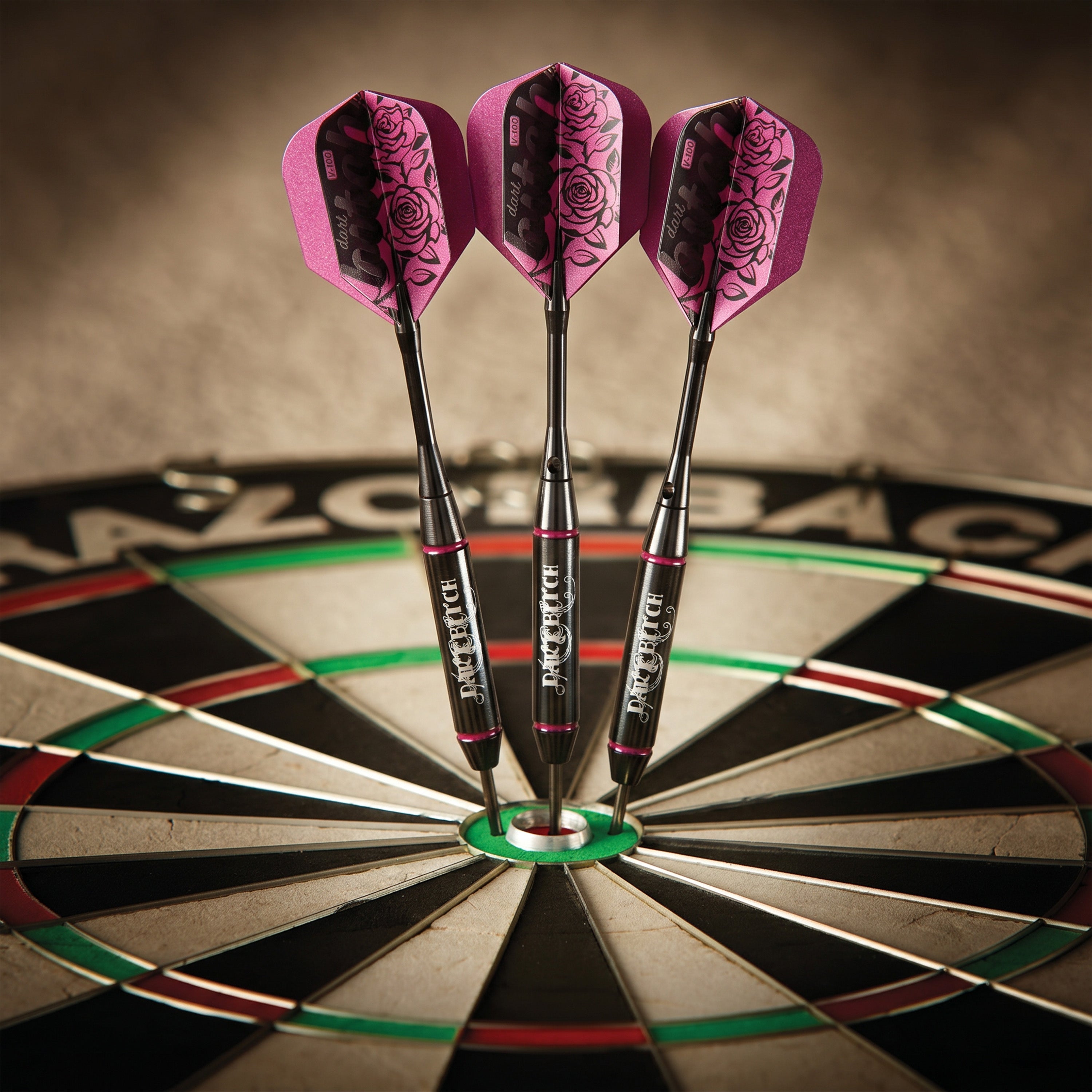 Three Dart Bitch darts grouped in a bristle dartboard with pink rose flights
