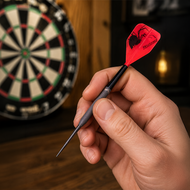 Hand holding a Laserdarts Black Widows Movable Point Smooth Steel Tip with a red and black spider design in front of a dartboard.