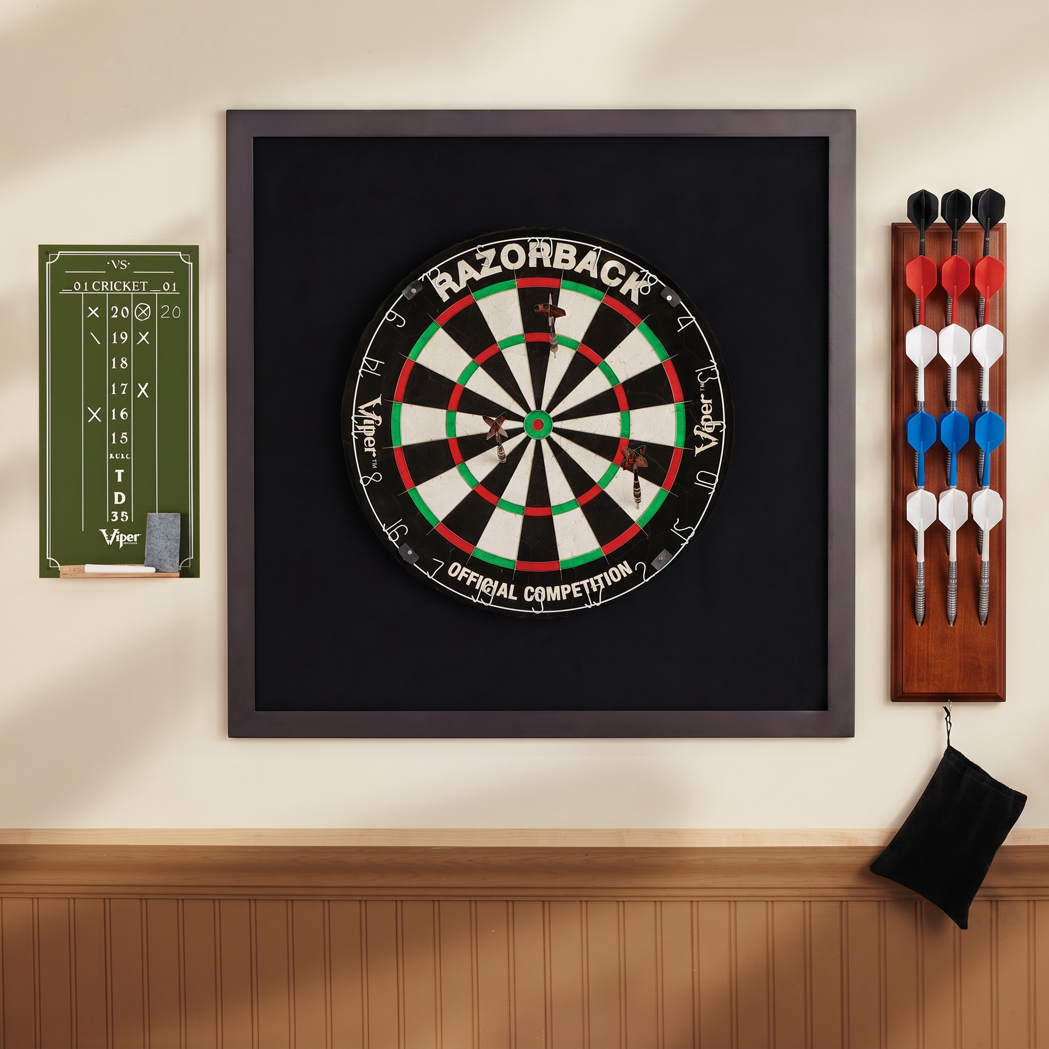 Dartboard with red, green, white segments in dark frame beside dart holder and scoreboard