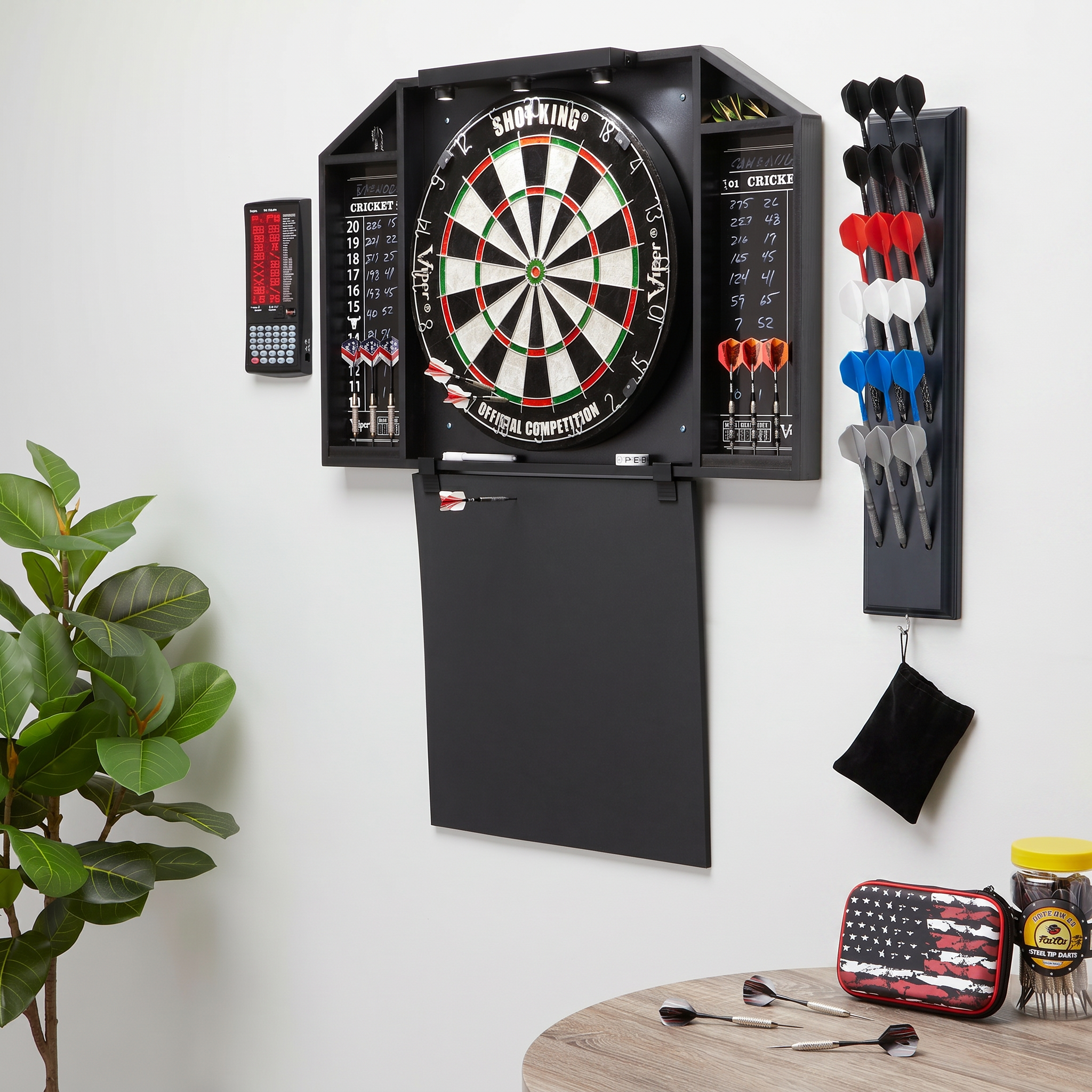 Electronic dartboard mounted on wall with dart storage rack holding red, white, and blue darts