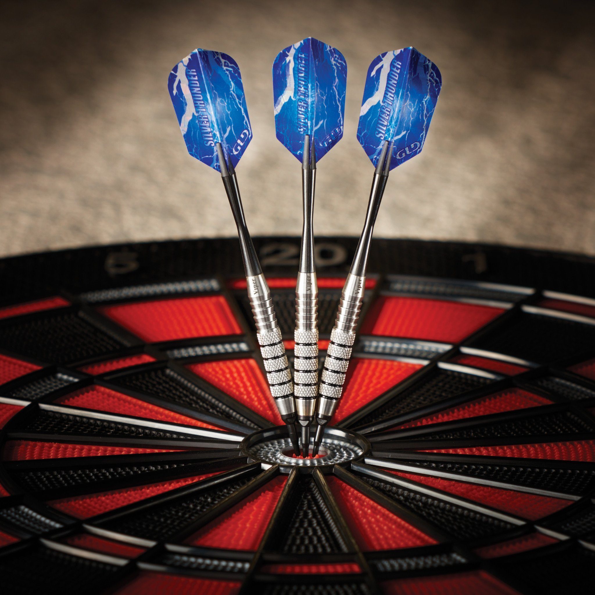 Three darts with blue flights and silver barrels in a dartboard with red and black segments