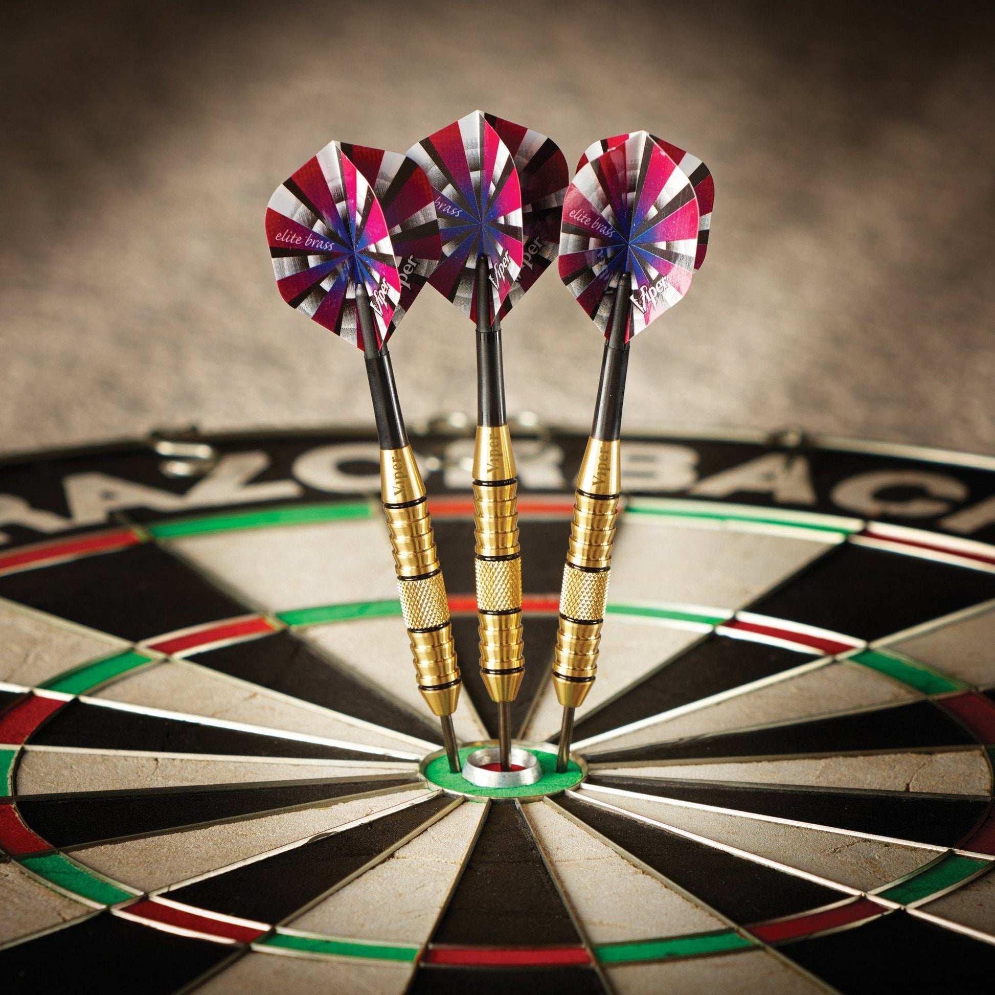 Three darts with red, pink, and white striped flights and brass bodies in the bullseye of a dartboard