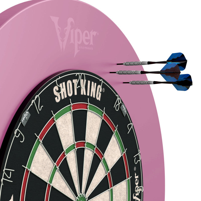 Pink dartboard surround behind a black and red dart board with three blue darts embedded in the upper right