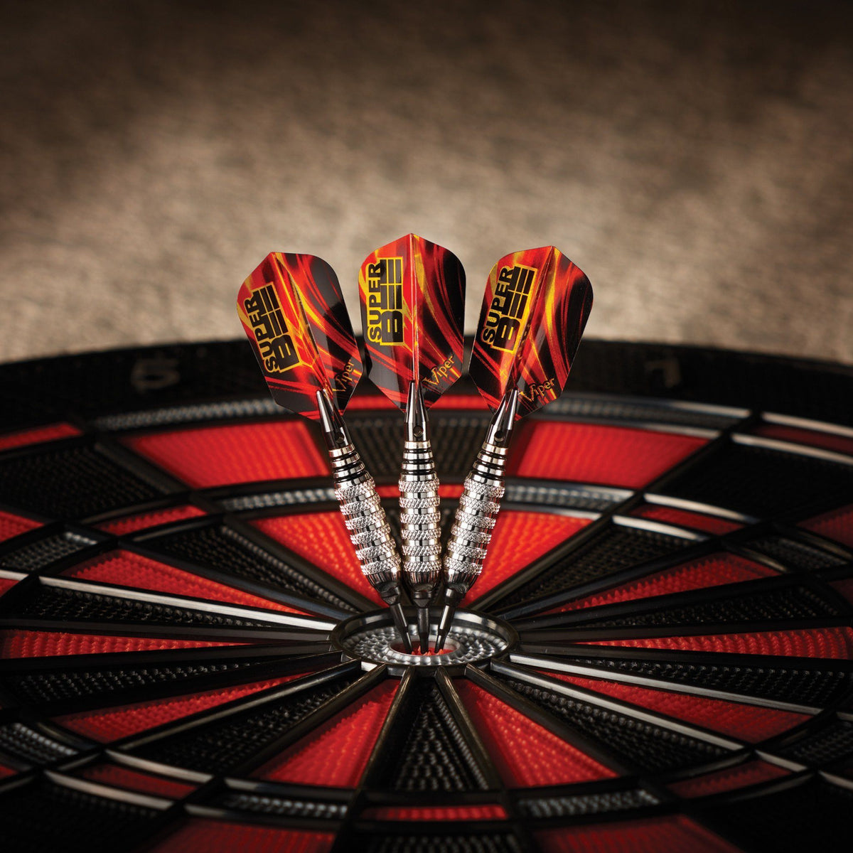 Three darts with red and black flights in dartboard center