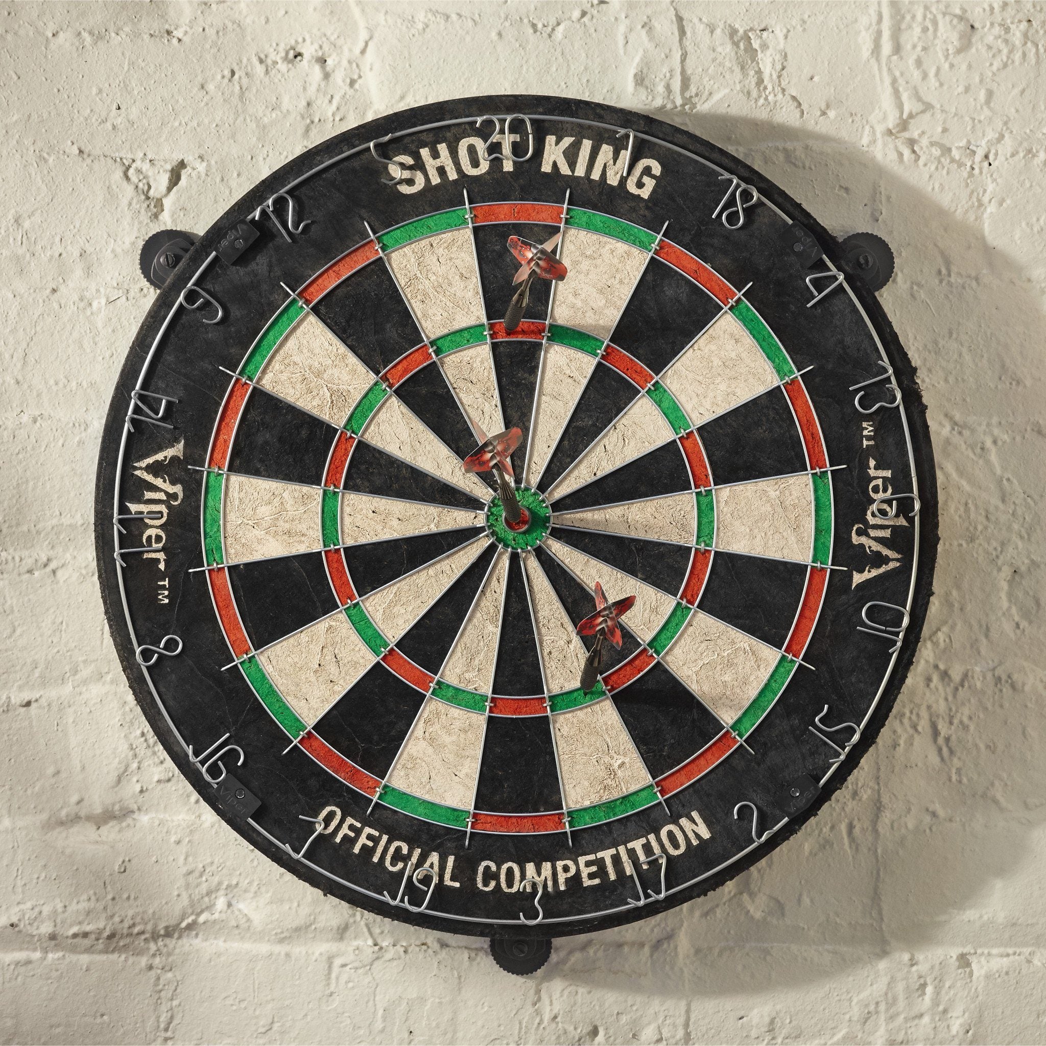 Black dartboard with red and green rings, cream wedges, two darts in center, numbered 1-20 around edge