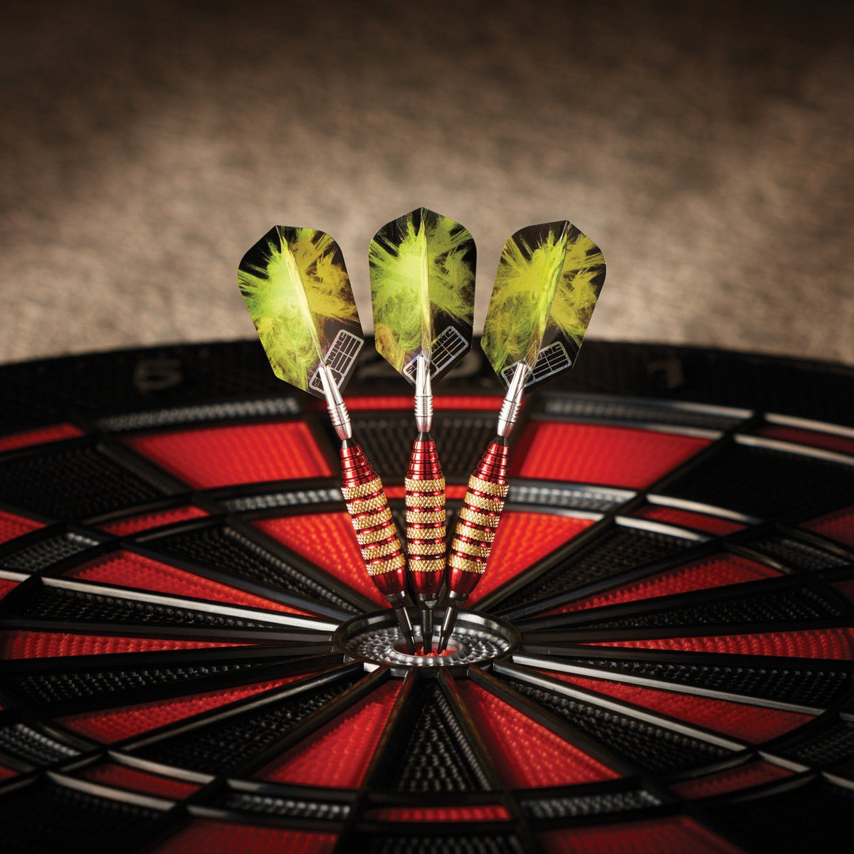 Three darts with yellow flights and red barrels stuck in dartboard bullseye