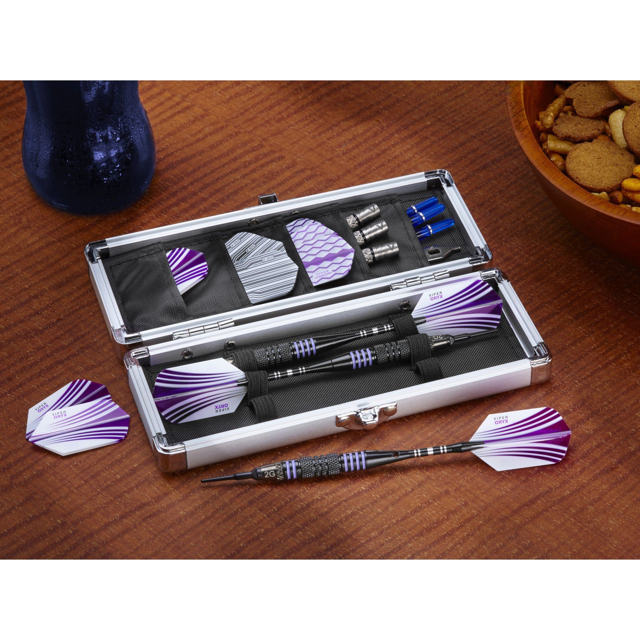 Aluminum case holding purple and white striped darts with black barrels on wood surface