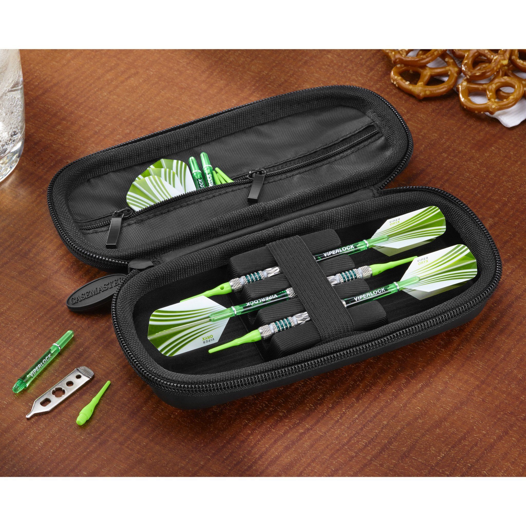 Black dart case with zipper containing green and white striped darts and flight tools on wooden surface