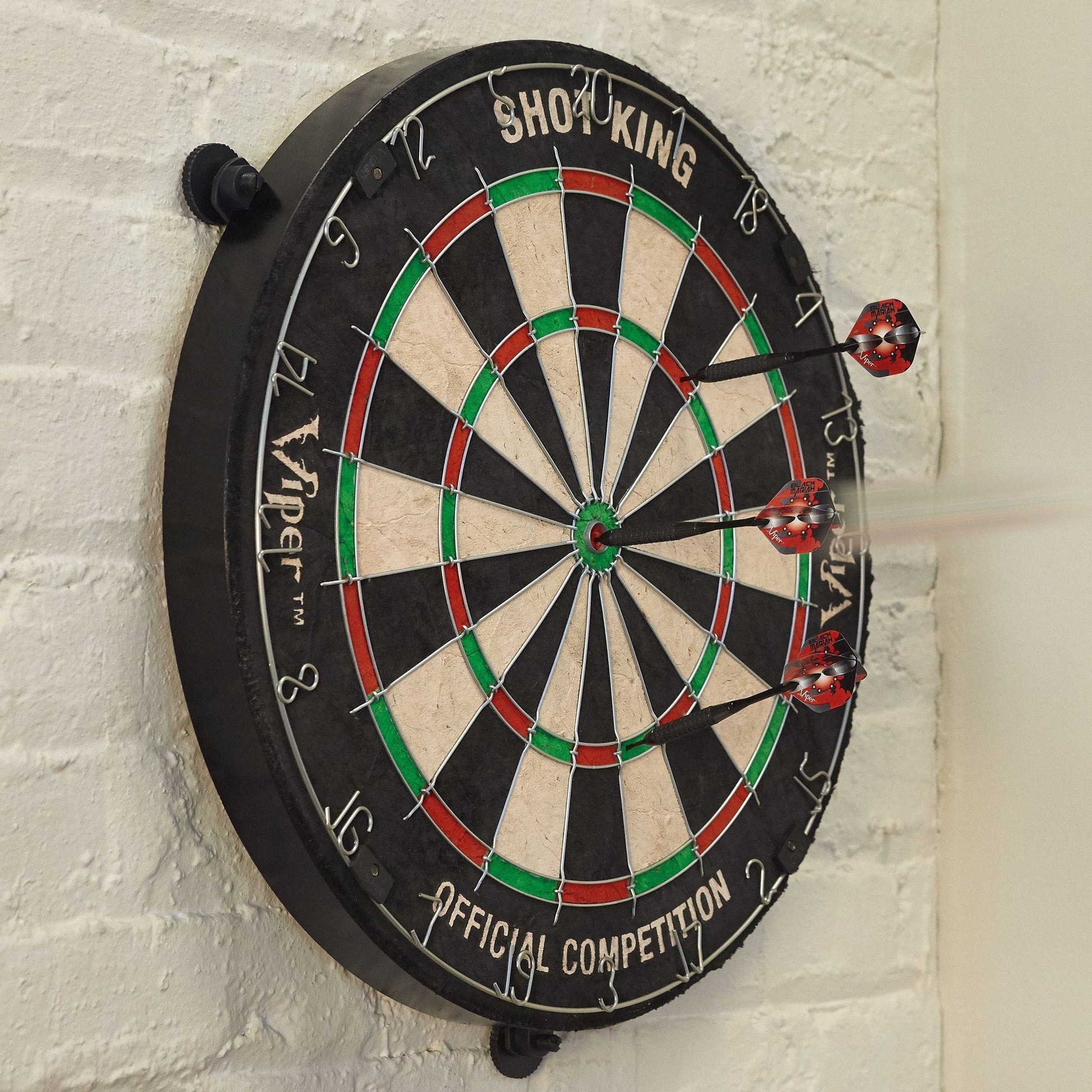 Dartboard with black rim, cream and black wedges, red and green sections, three red darts inserted