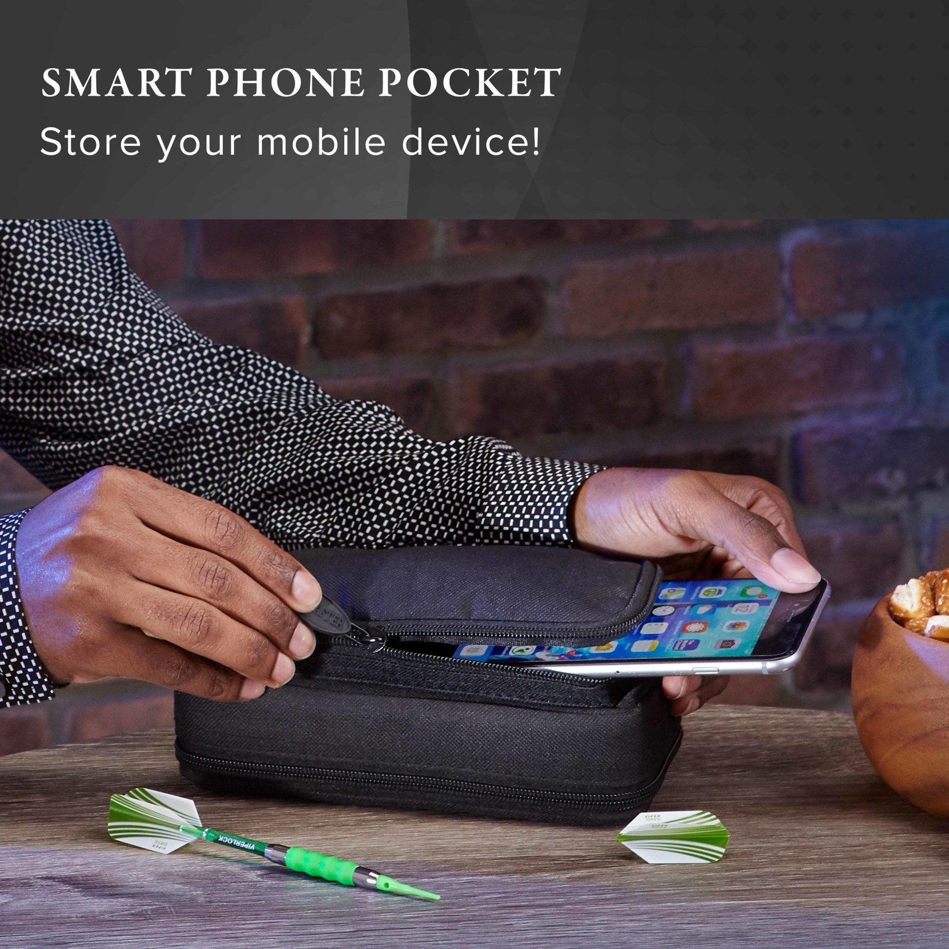 Black zippered pouch with smartphone and green darts on wooden table