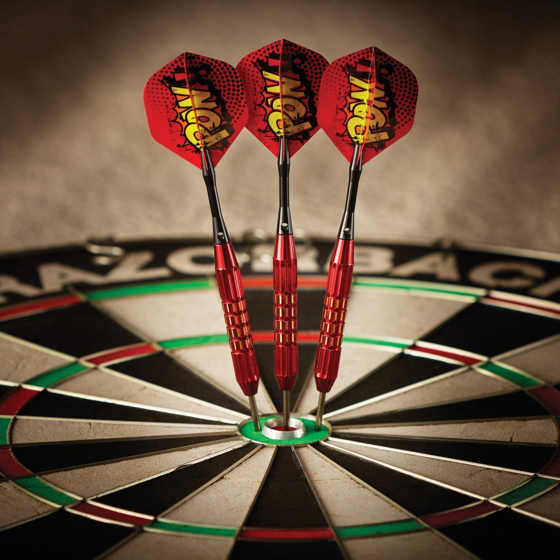 Three red darts with yellow flights in dartboard center bullseye