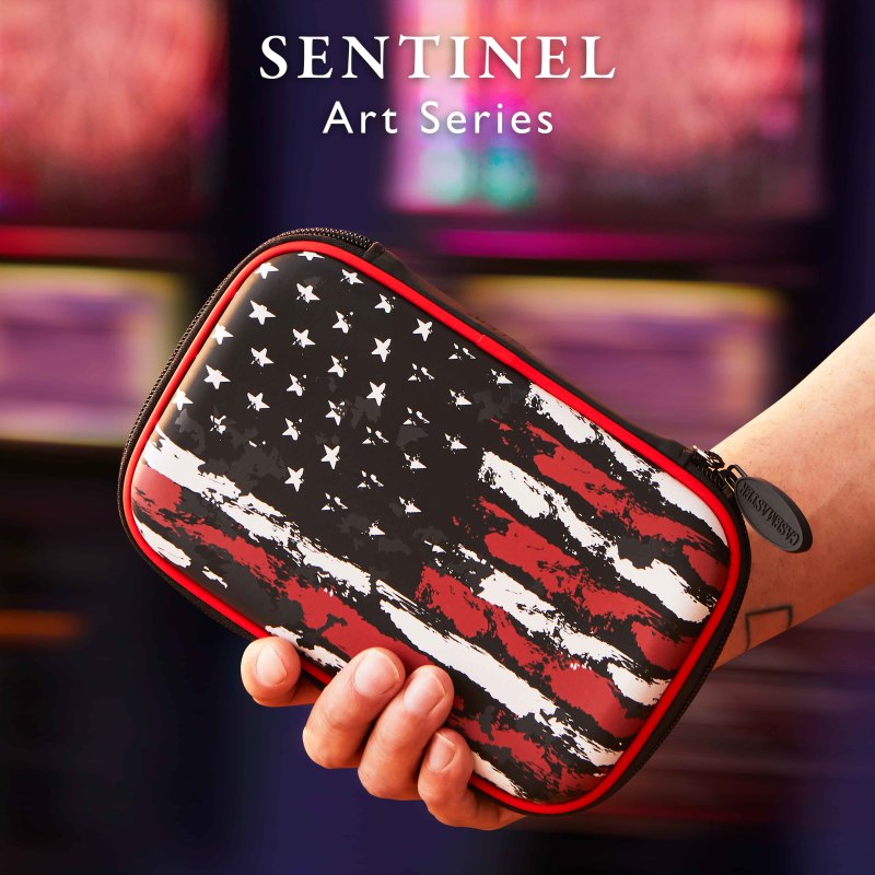 A person's hand holding a black, red, and white distressed flag patterned dart case with red trim and zipper