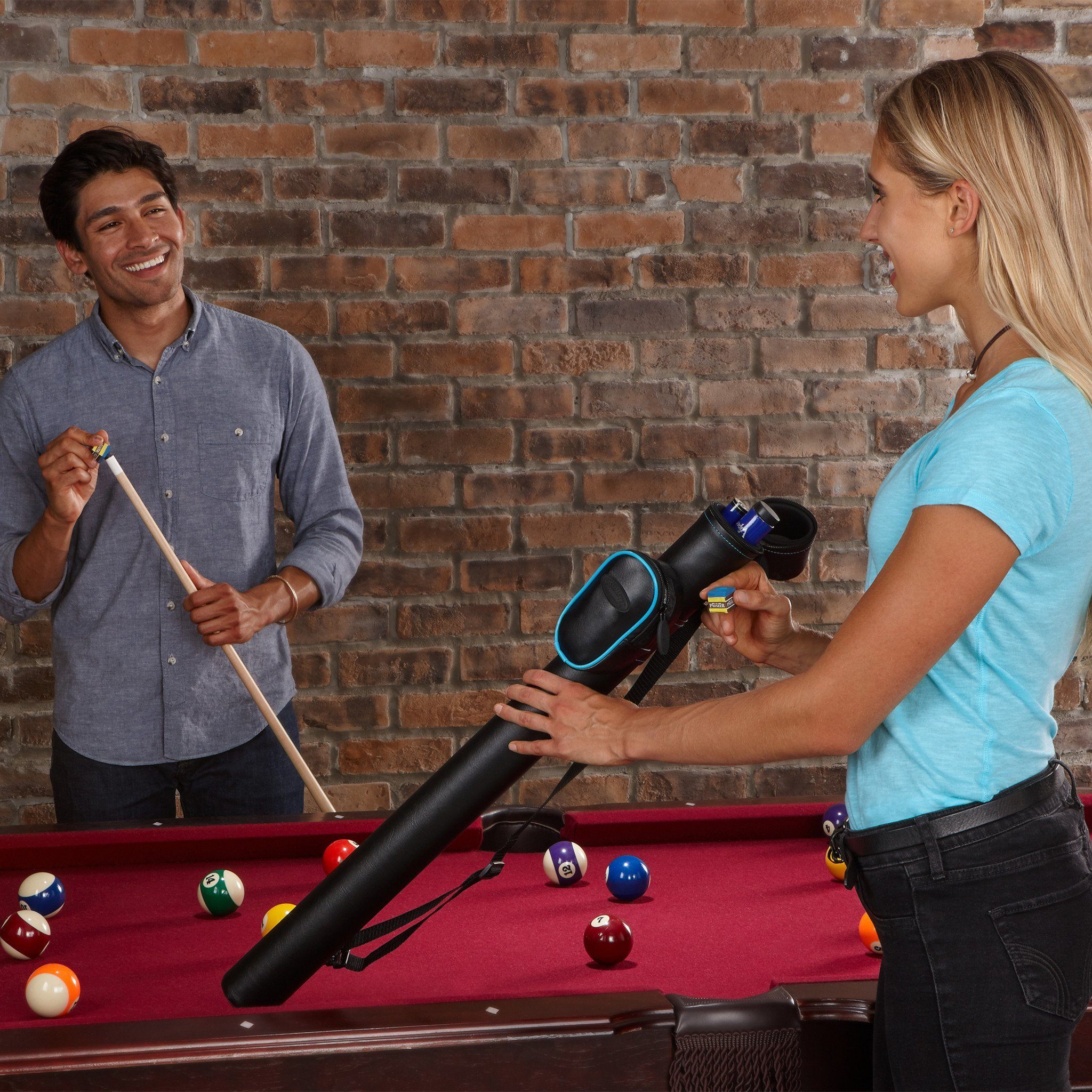 Two people at a billiards table, one holding a cue stick, one holding a black case with blue trim