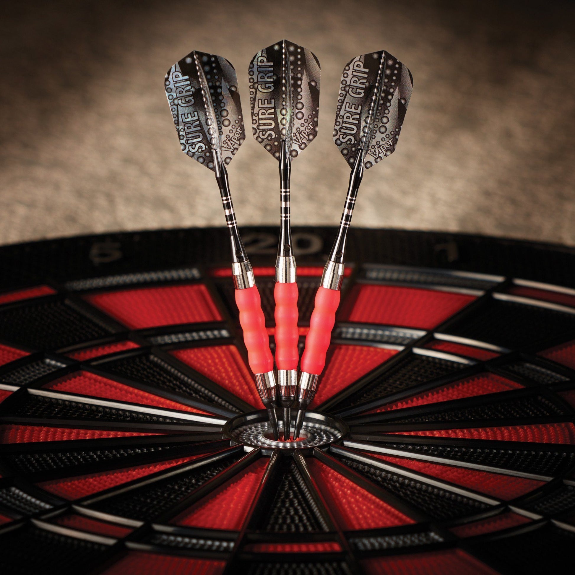 Three darts with pink grips and studded black flights in a dartboard