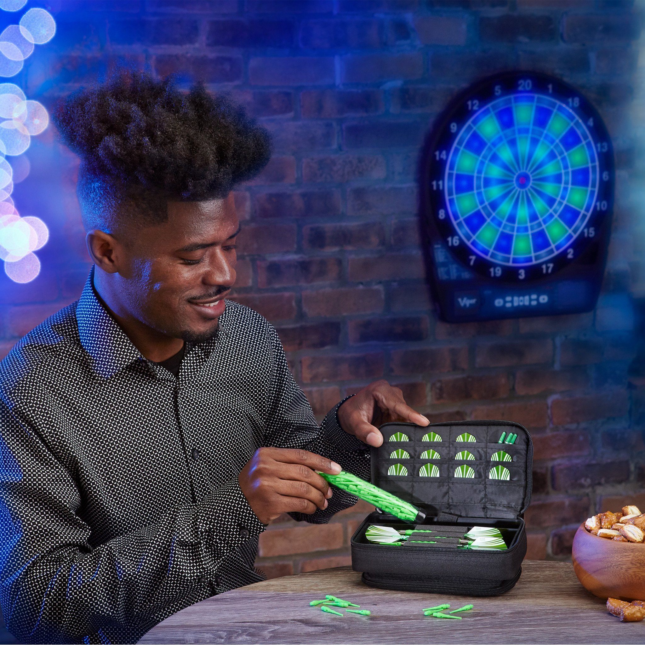 A person opens a black case filled with green and white darts indoors