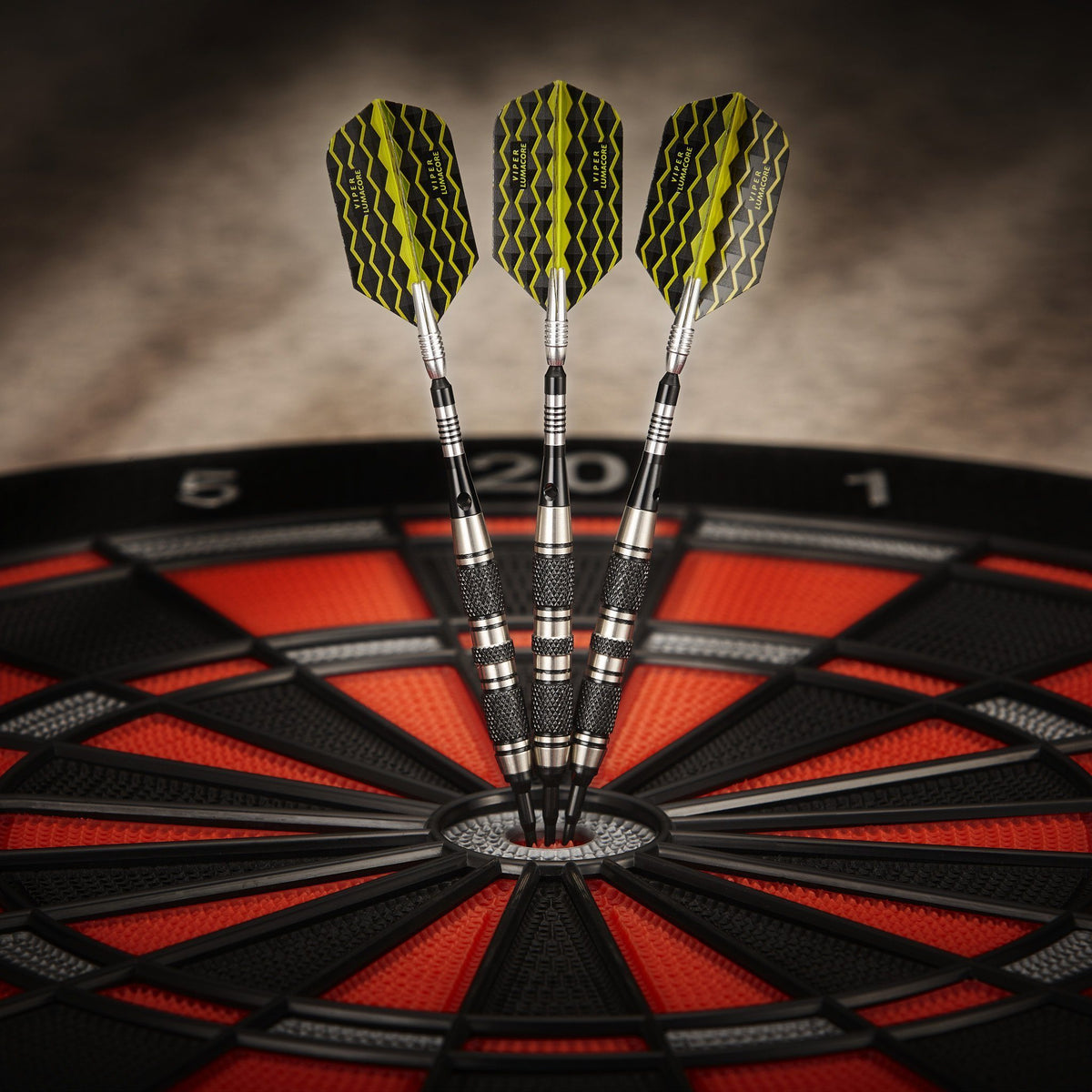 Three yellow and black wavy-patterned darts with silver barrels stuck in a red and black dartboard