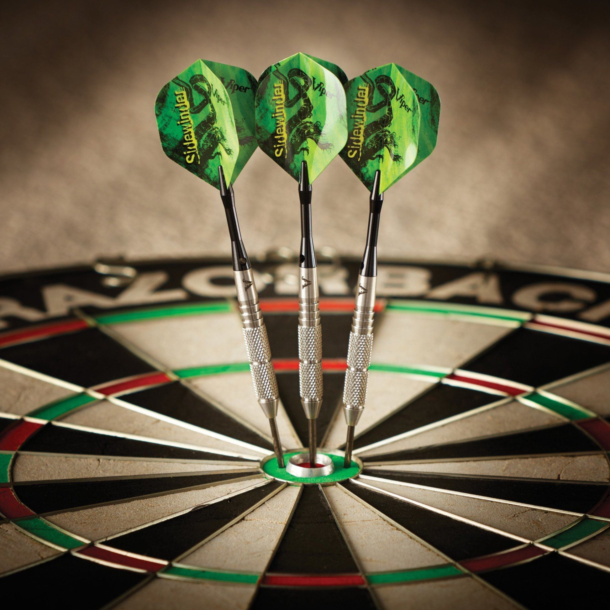 Three green darts with metal barrels stuck in a dartboard