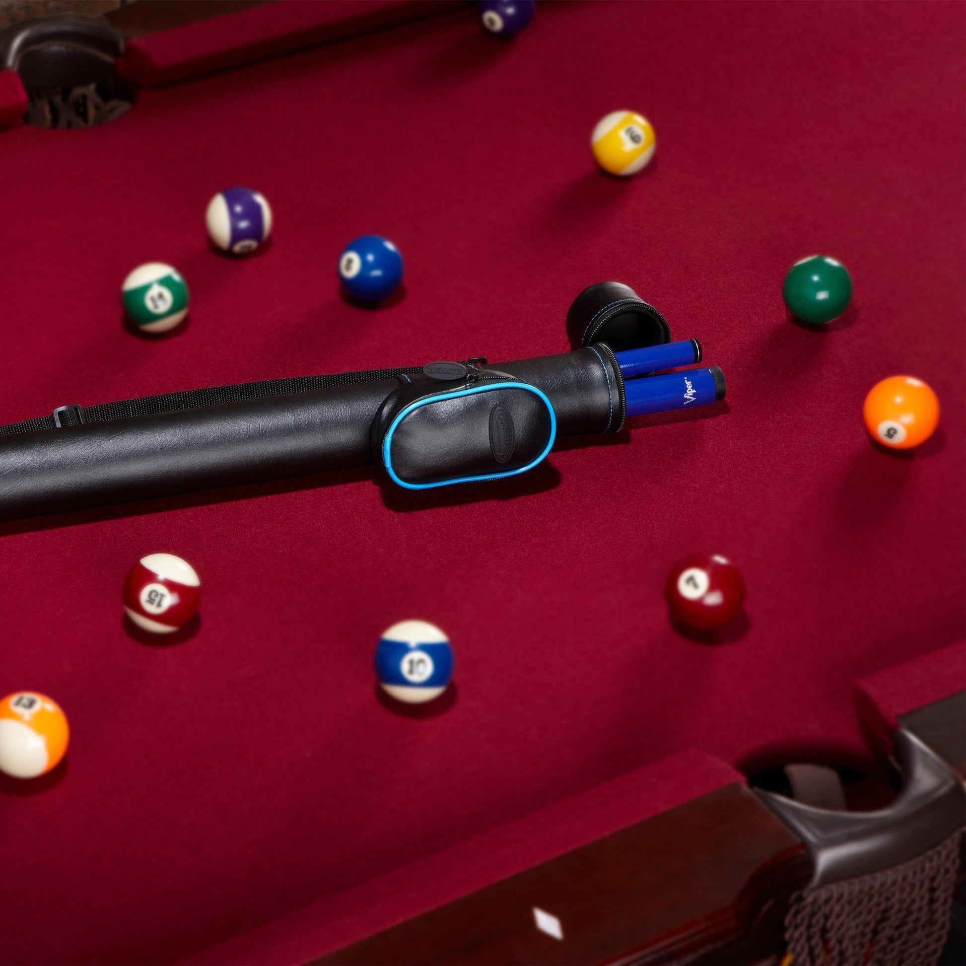 Black cue stick with blue accents on burgundy pool table with numbered balls