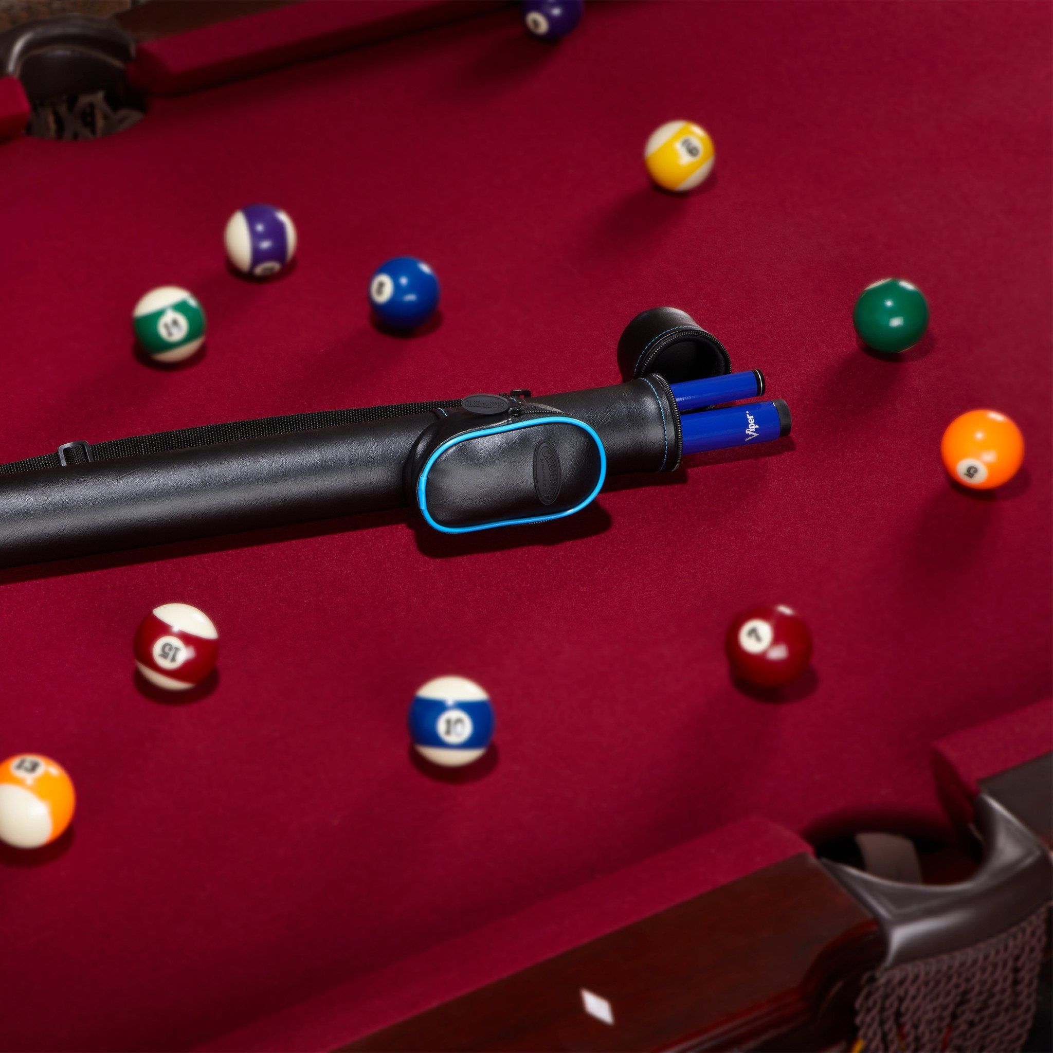 Black cue stick with blue accents on burgundy pool table with numbered balls