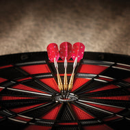 Three red darts with white stars in dartboard bullseye