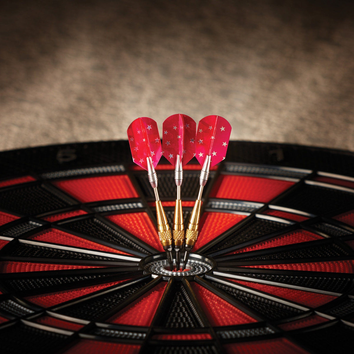 Three red darts with white stars in dartboard bullseye