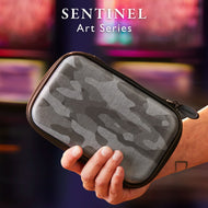 A person holds a black dart case with gray camouflage pattern and gold zipper