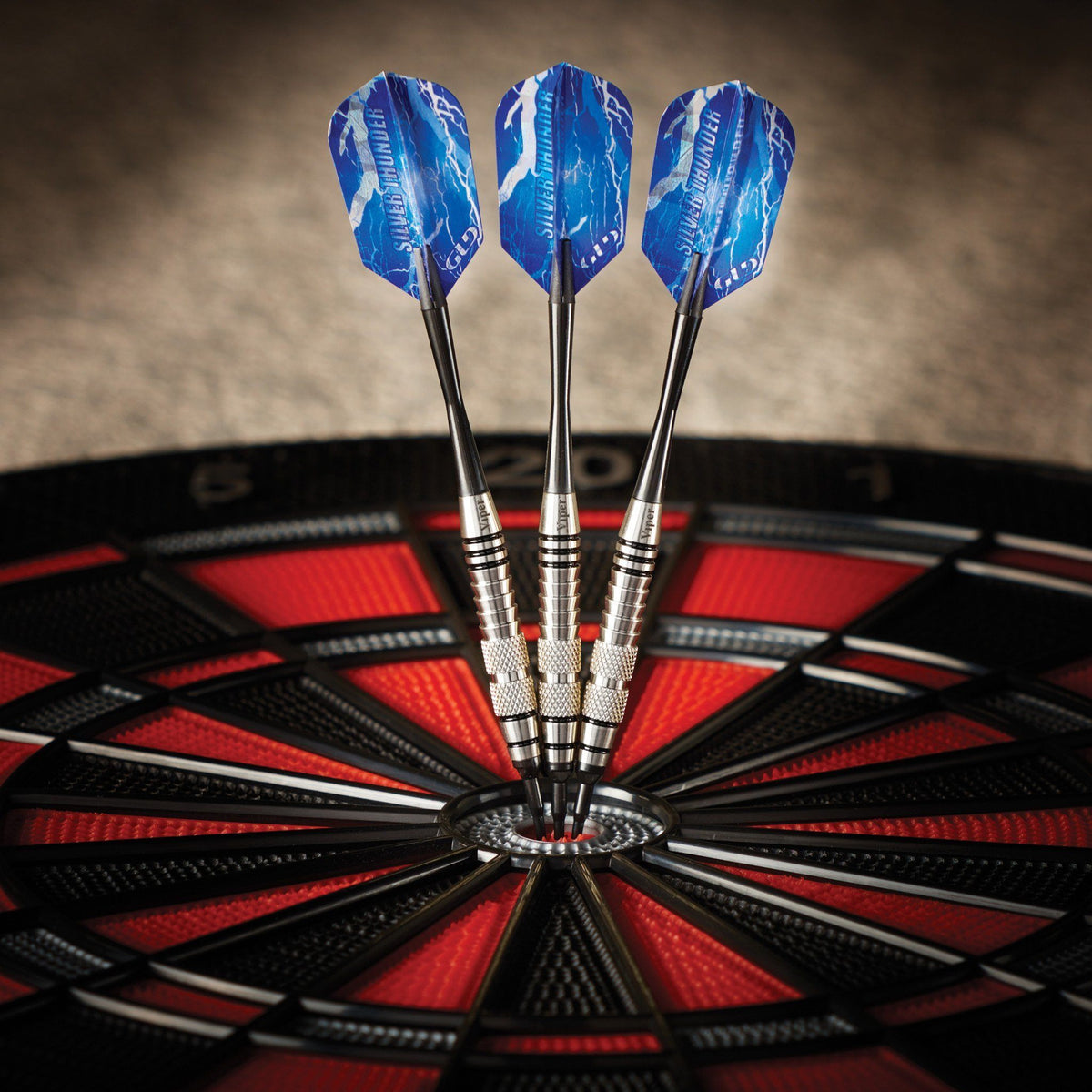 Three blue darts with metal barrels in a dartboard bullseye with red and black segments