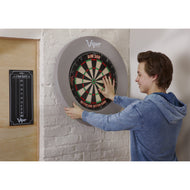 A person in a blue hoodie reaches toward a gray Viper dartboard on a white brick wall