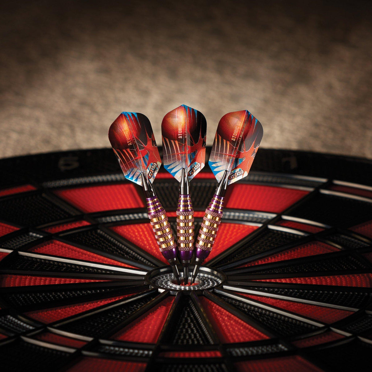 Three darts with red and blue flights in dartboard bullseye