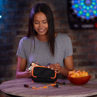 A person opens a black dart case with orange trim at a wooden table