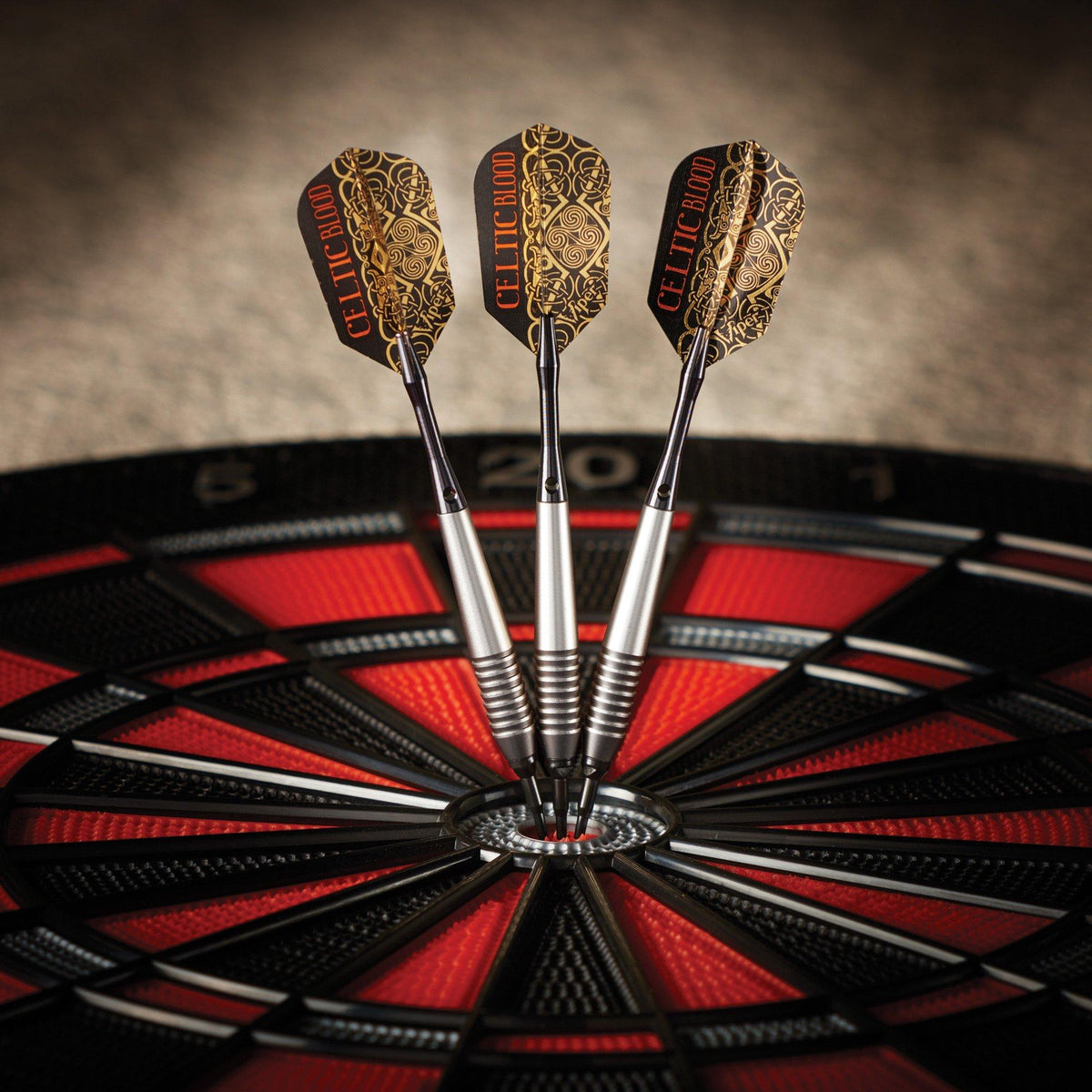 Three darts grouped in the bullseye with black-and-gold Celtic knotwork flights and silver barrels.